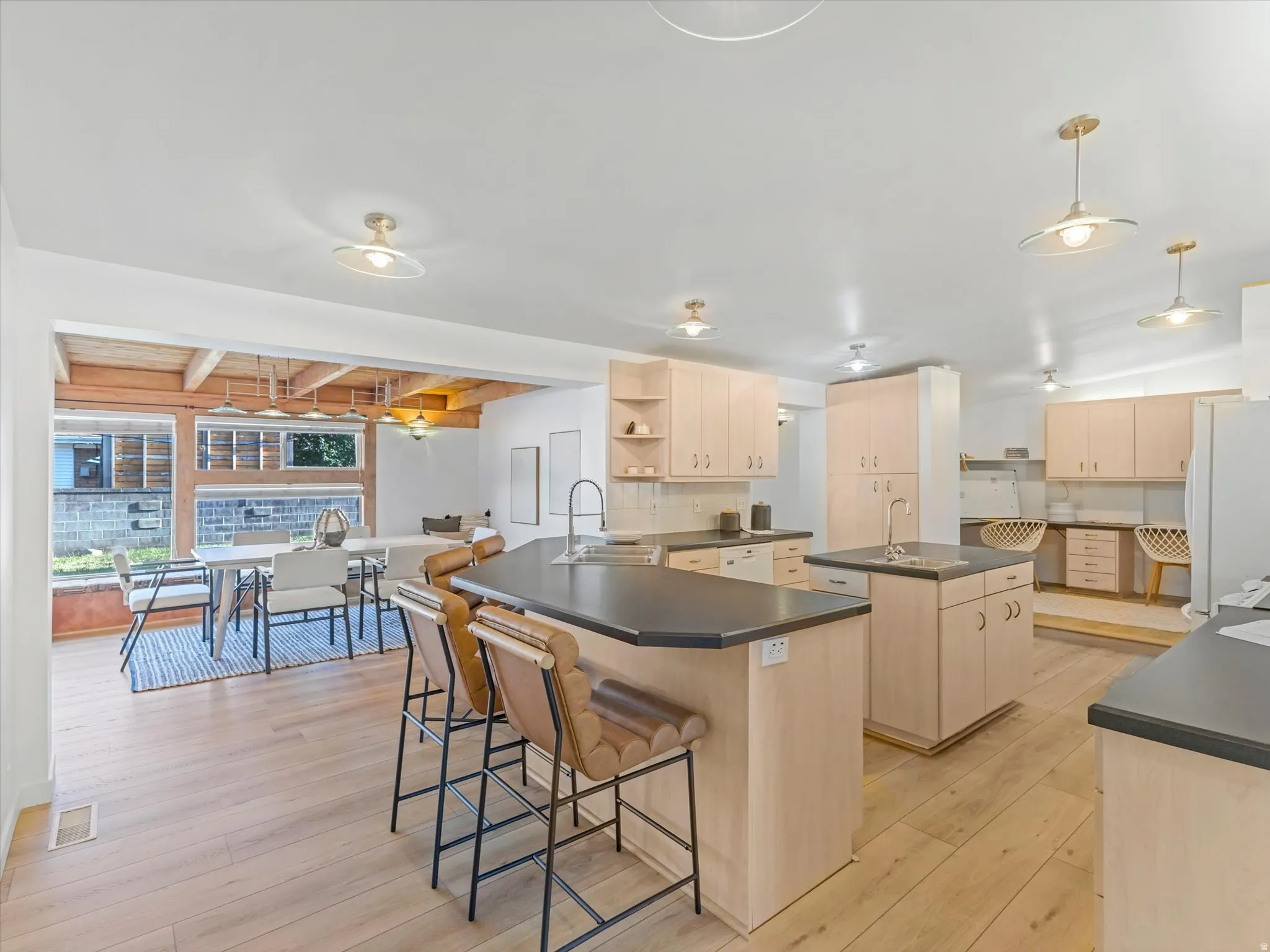 Expansive kitchen featuring light wood-finish cabinetry, dark countertops, and wood-finish flooring