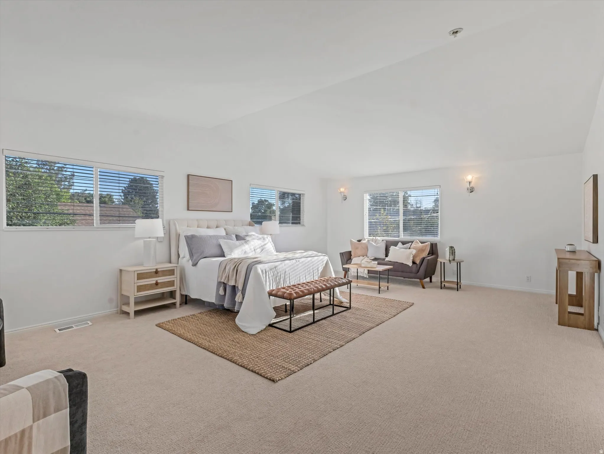 Expansive 700 Square Foot Primary Bedroom featuring vaulted ceilings, recessed lighting, and wall-mounted sconces
