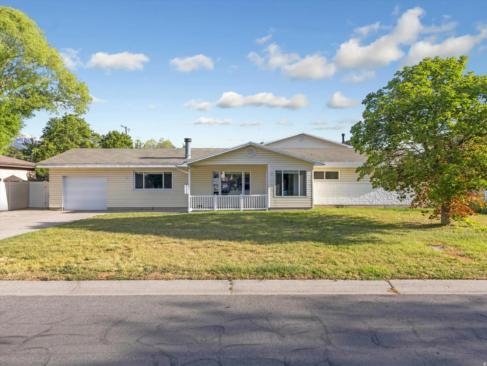 Ranch-style residence featuring light-colored siding and a covered front porch with white railing