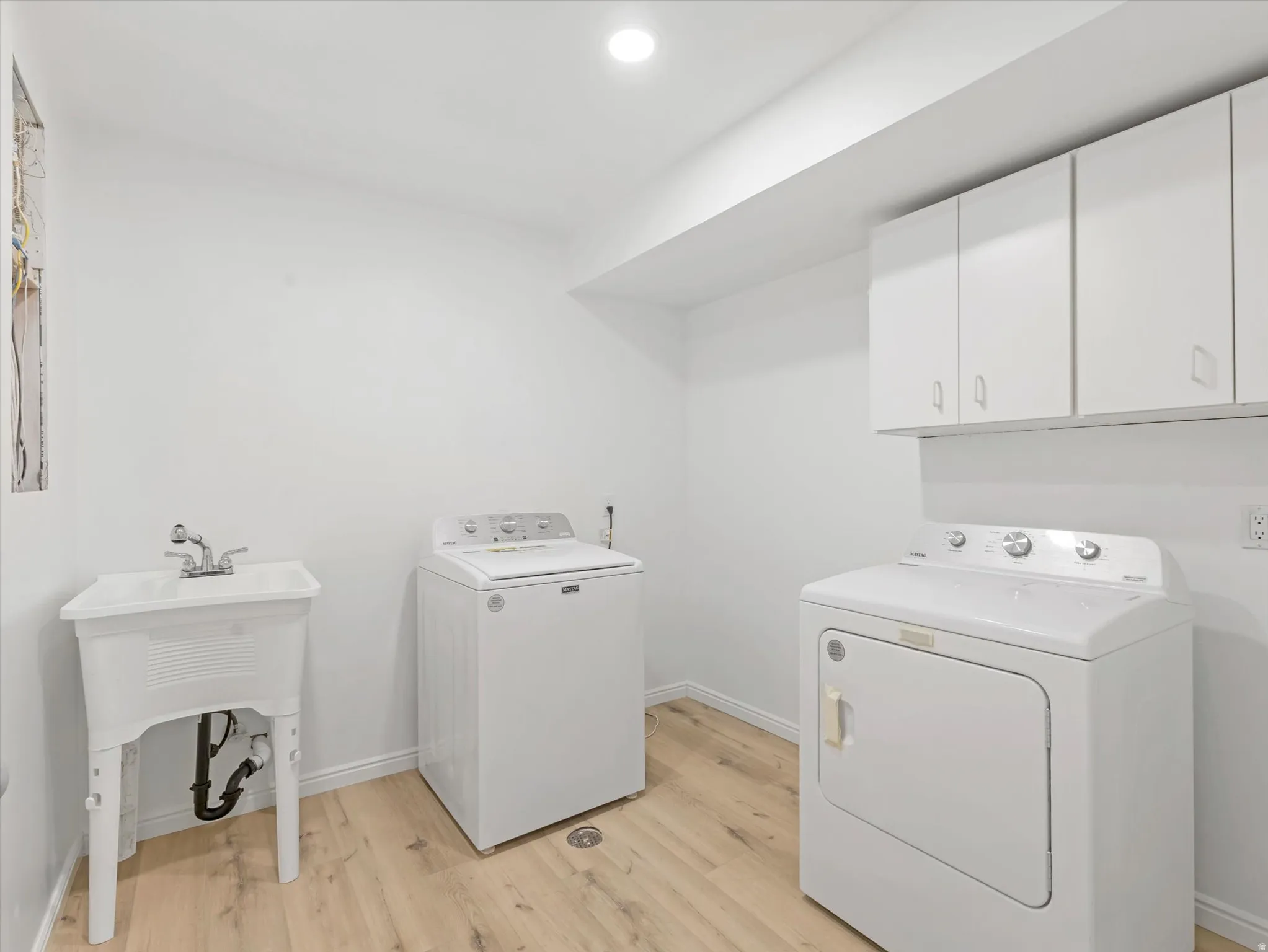 Dedicated laundry space featuring wood-finish flooring, white walls, and recessed lighting