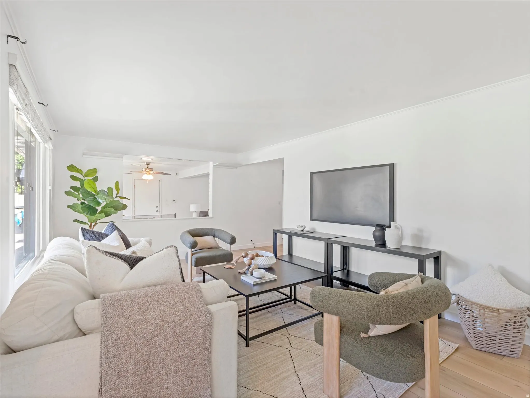 Bright living area featuring light wood-finish flooring, white walls, and crown molding