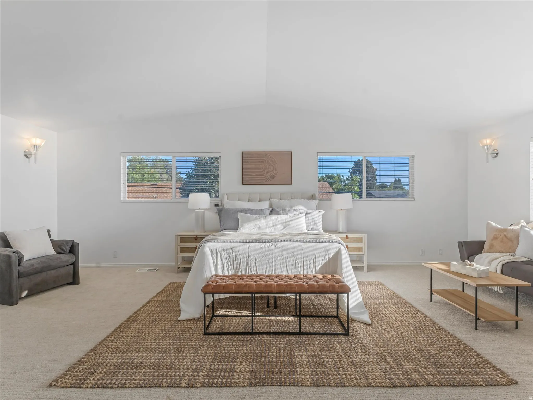 Expansive 700 Square Foot Primary Bedroom featuring vaulted ceilings, recessed lighting, and wall-mounted sconces