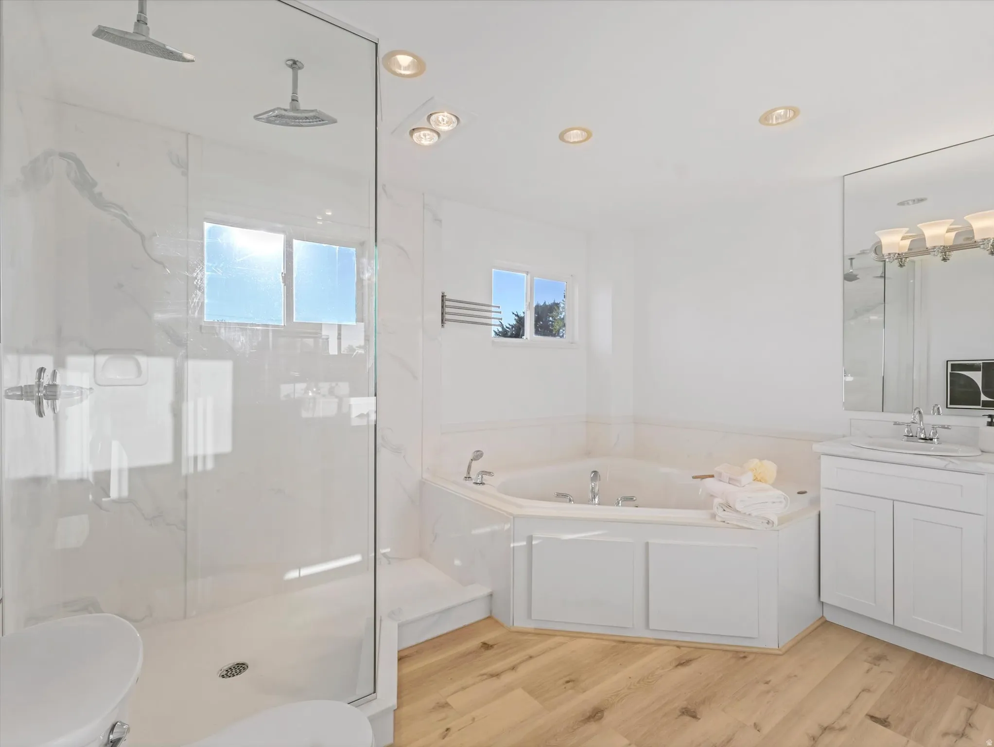 Primary En-Suite featuring a spacious corner soaking tub and a glass-enclosed shower with dual rainfall showerheads