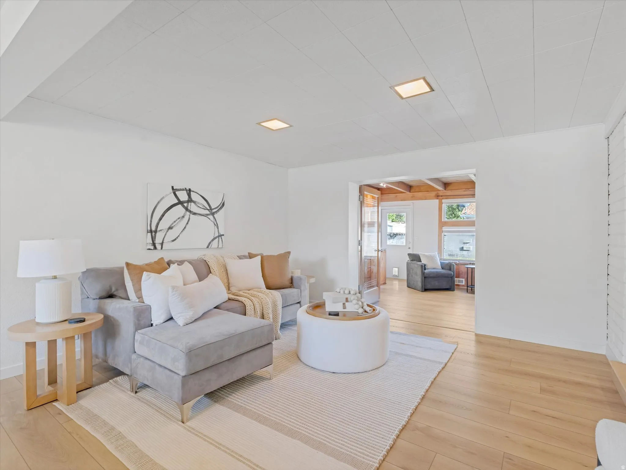 Spacious living area featuring light wood-finish flooring, recessed lighting, and a paneled ceiling