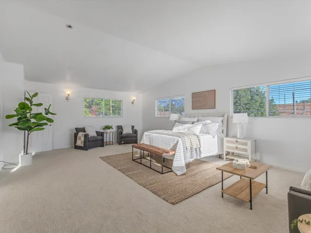 Expansive 700 Square Foot Primary Bedroom featuring vaulted ceilings, recessed lighting, and wall-mounted sconces