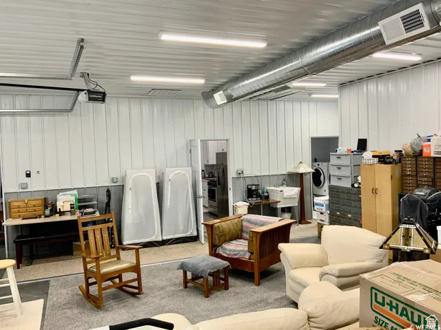 Spacious interior featuring a white corrugated metal wall finish, exposed spiral ductwork, and fluorescent strip lighting