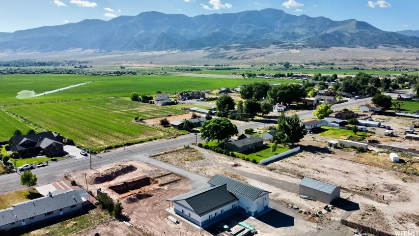 Expansive mountain backdrop framing a rural landscape featuring a mix of agricultural fields and residential properties