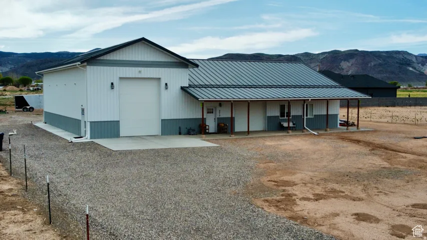 Modern barn-style structure featuring a large garage door and a covered porch