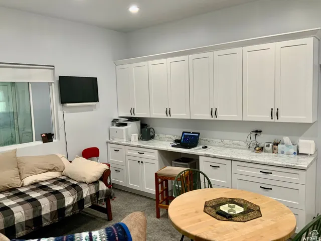Built-in white shaker-style cabinetry with crown molding, black hardware, and an integrated desk area