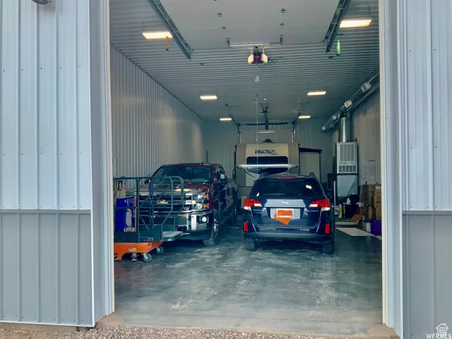 Spacious garage featuring a large overhead door, corrugated metal walls, concrete flooring, and overhead lighting