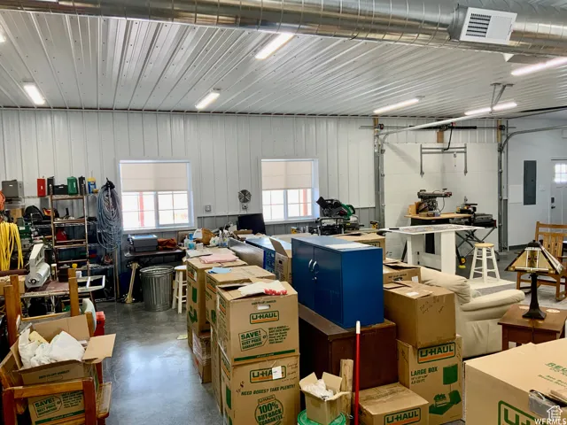 Spacious workshop featuring a durable concrete floor, two large overhead doors, and multiple windows for natural light