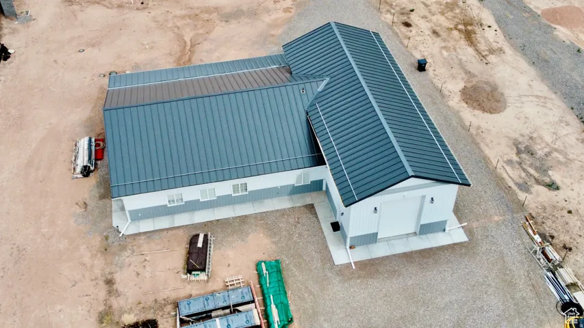 Modern industrial-style building featuring a dark gray metal roof, light gray and white exterior siding, and a large garage door