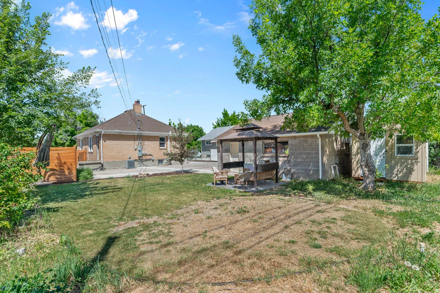 Expansive backyard featuring a shaded gazebo, mature trees, and a detached shed