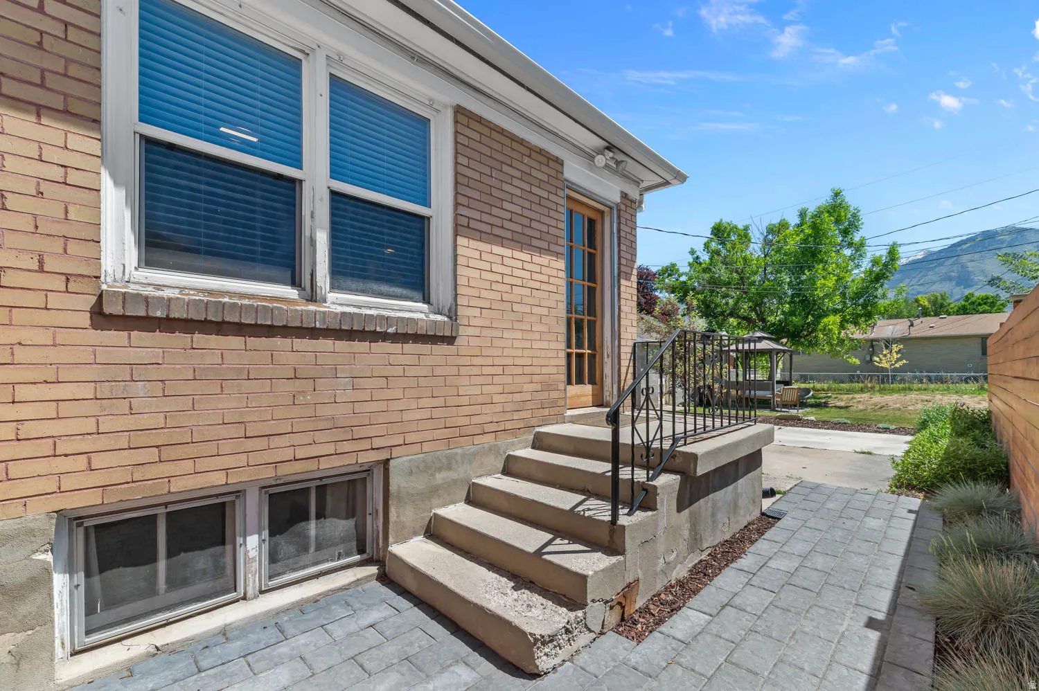 Brick exterior with paved walkway and concrete steps featuring a wrought iron railing