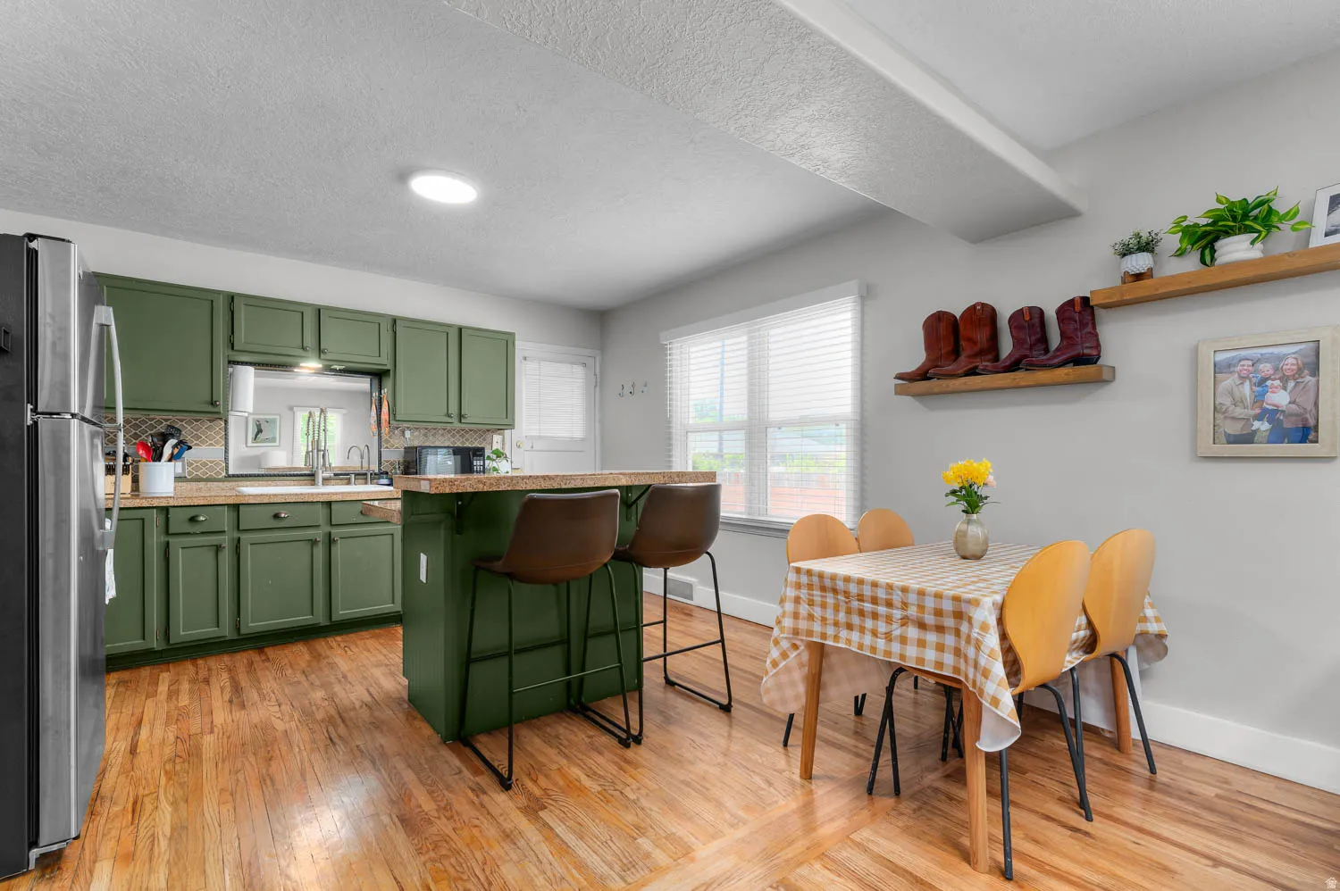 Kitchen featuring wood-finish flooring, green cabinetry, a tiled backsplash, and a breakfast bar with seating