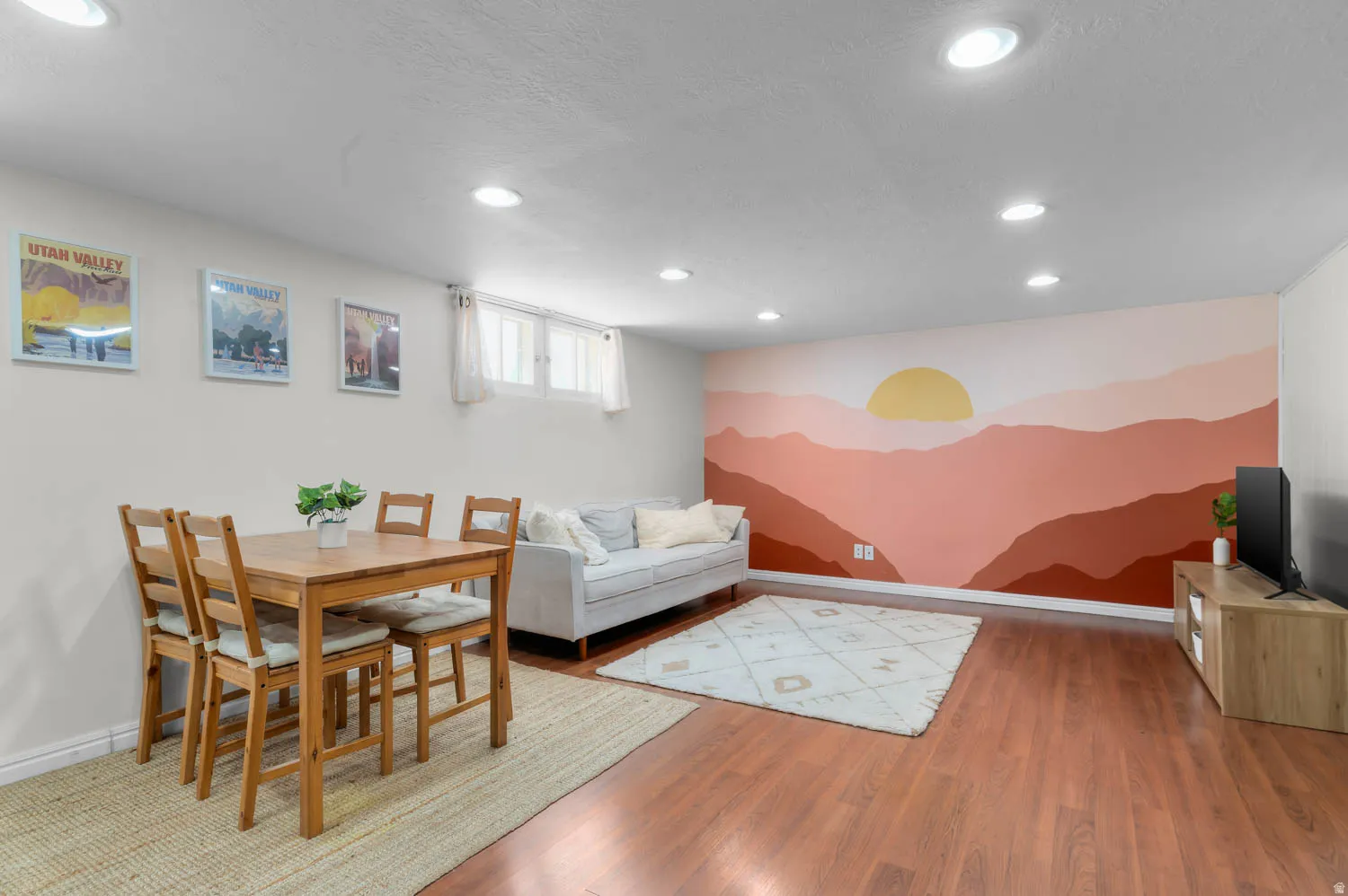 Spacious living area featuring a custom painted mural wall, recessed lighting, and wood-finish flooring
