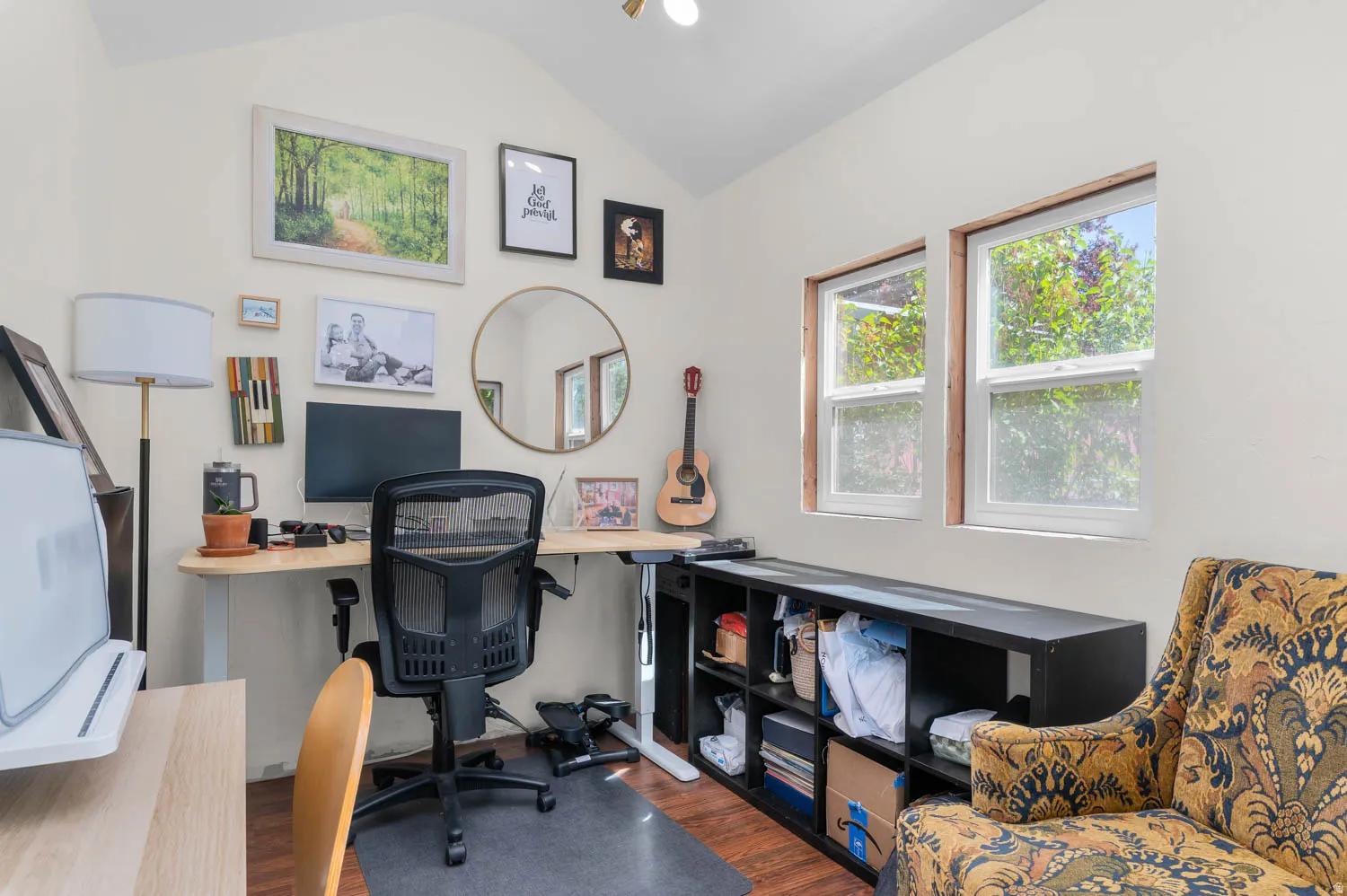 Vaulted ceiling room with two double-hung windows, wood-finish flooring, and light-toned walls
