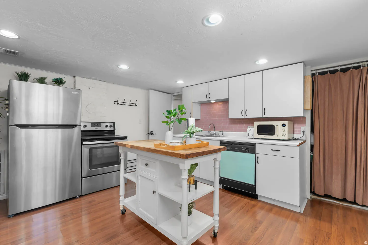 Kitchen featuring wood-finish flooring, recessed lighting, and white cabinetry