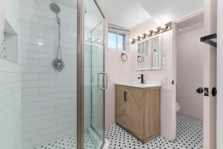 Bathroom featuring a glass-enclosed shower with subway tile, a shower niche, and a black-and-white hexagonal tile floor