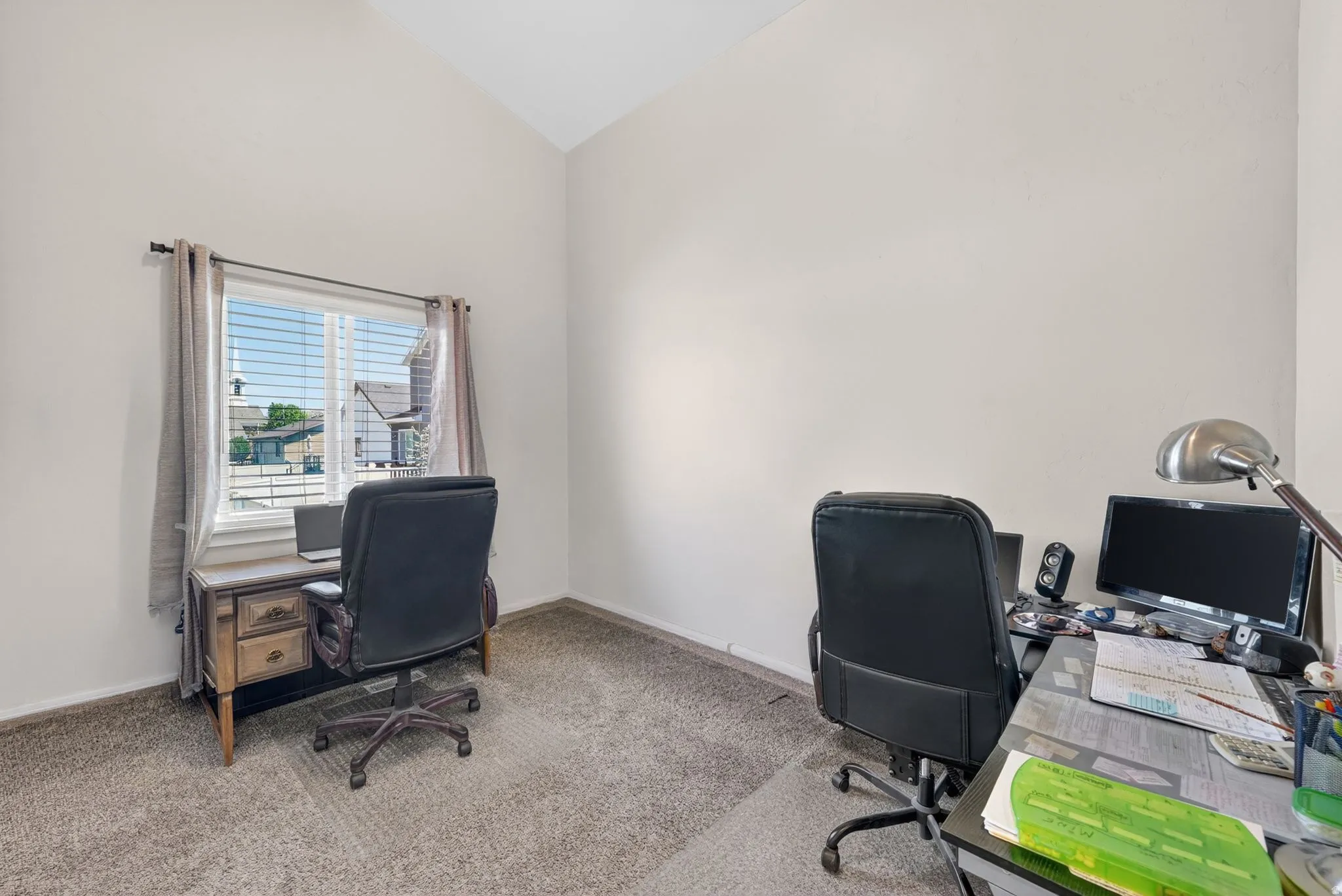 Room featuring neutral-toned walls, vaulted ceilings, and a single window with horizontal blinds