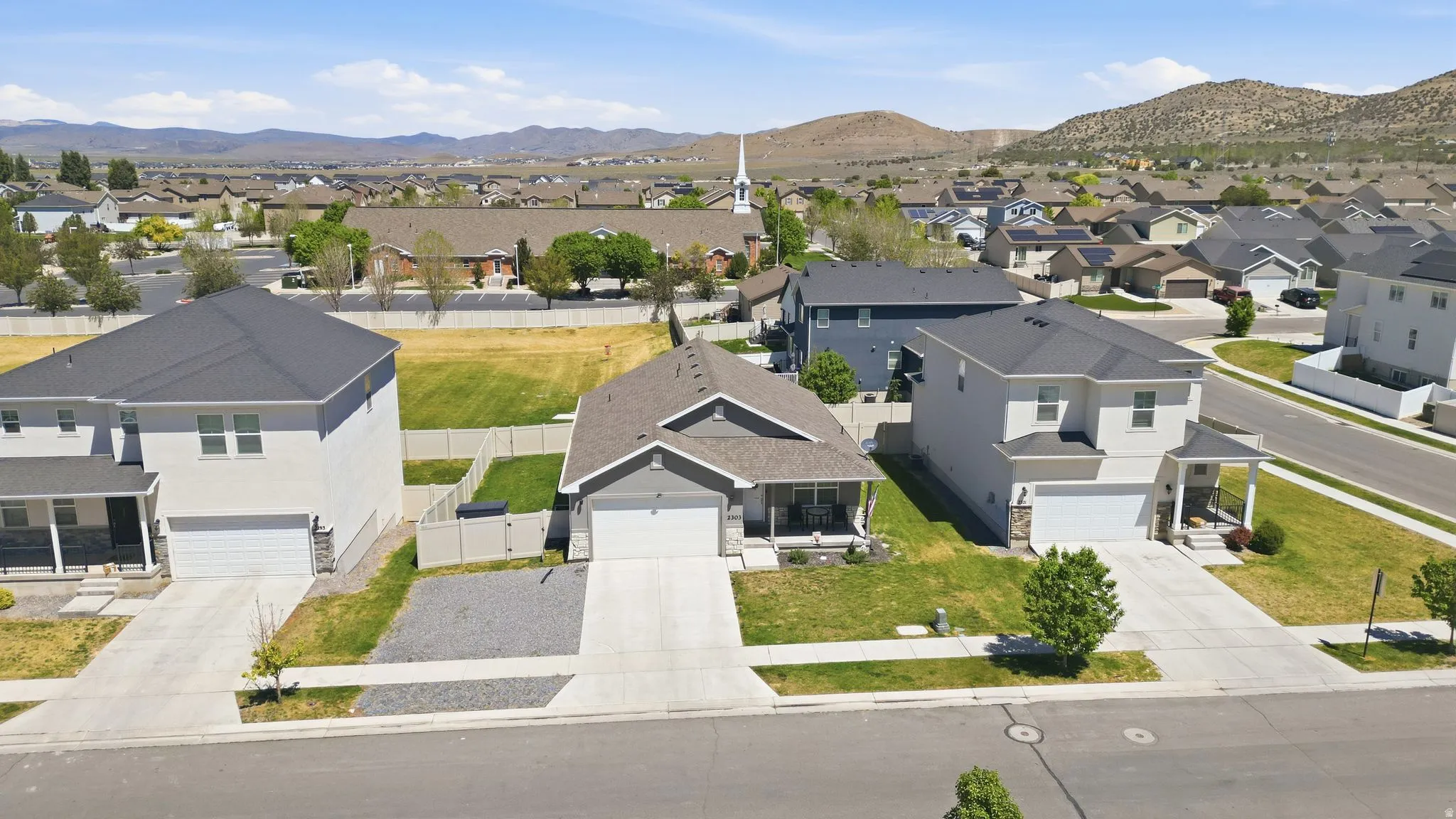 Suburban setting featuring multiple homes with pitched roofs, paved driveways, and landscaped front yards