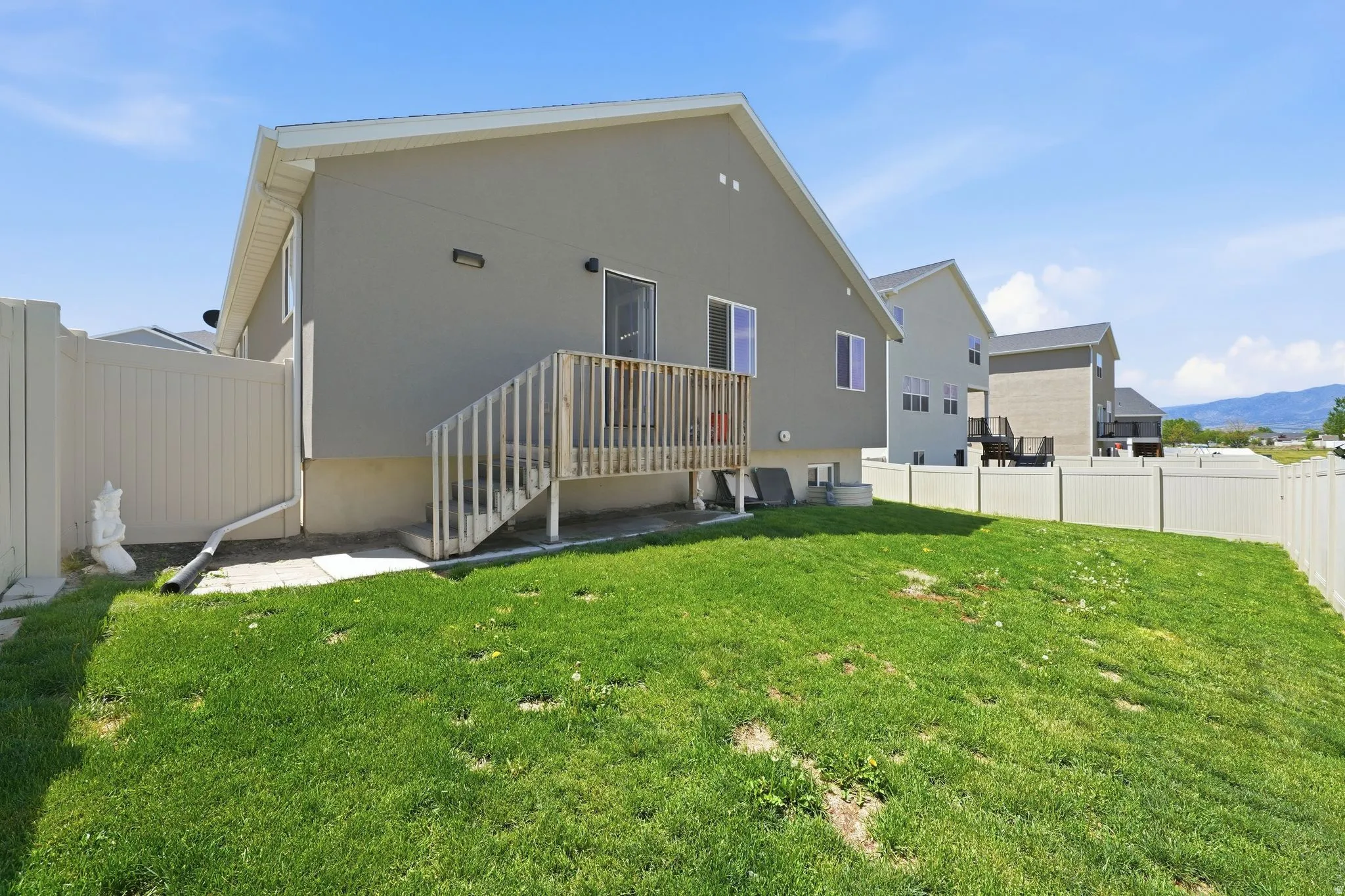 Fenced backyard featuring a wood deck and stairs, with a sliding glass door providing access to the interior