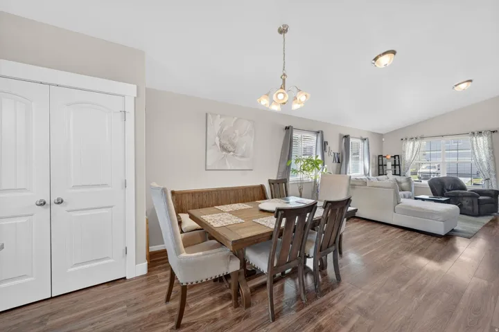 Open-concept dining area featuring wood-finish flooring, a contemporary chandelier, and light-toned walls