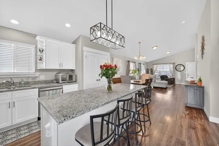 Kitchen island featuring a granite countertop with integrated seating, complemented by white cabinetry and stainless steel appliances