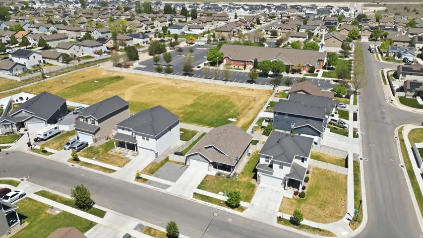 Expansive aerial perspective showcasing a developed residential community with multiple single-family homes and undeveloped land parcels