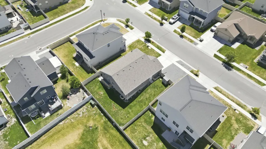 Aerial perspective of a residential neighborhood featuring asphalt streets, concrete sidewalks, and a variety of detached homes with fenced yards