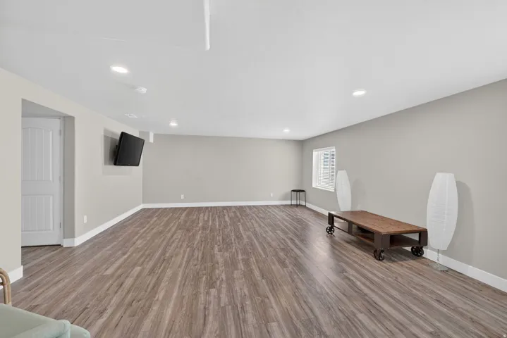 Spacious interior room featuring wood-finish flooring, recessed lighting, and light grey wall paint