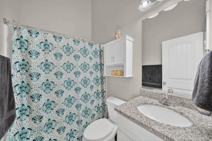 Bathroom featuring a white vanity with a speckled countertop and an undermount sink