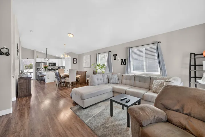 Spacious living area featuring wood-finish flooring, vaulted ceilings, and ample natural light from multiple windows