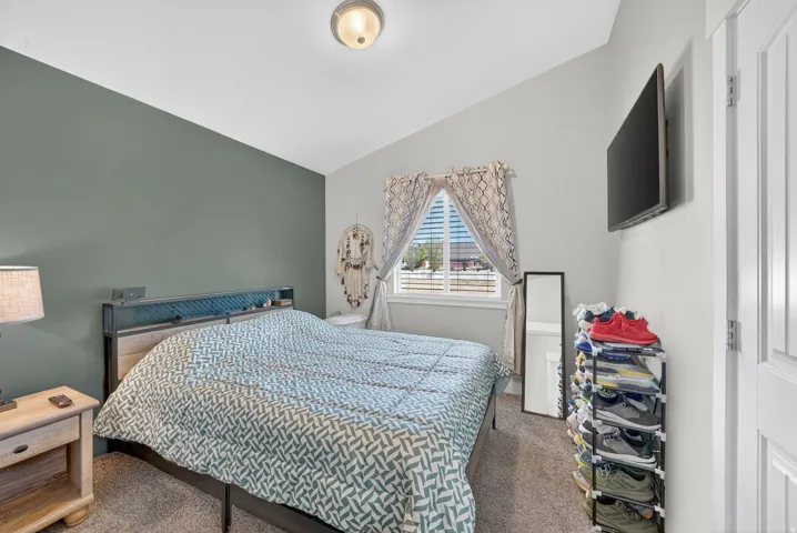 Bedroom featuring a vaulted ceiling and a contrasting accent wall