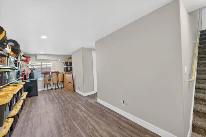 Lower level area featuring wood-finish flooring, light grey walls, and a recessed window