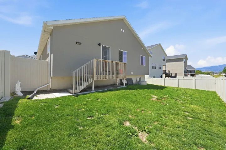 Fenced backyard featuring a wood deck and stairs, with a sliding glass door providing access to the interior