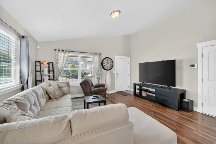 Spacious living area featuring wood-finish flooring, light-toned walls, and multiple windows