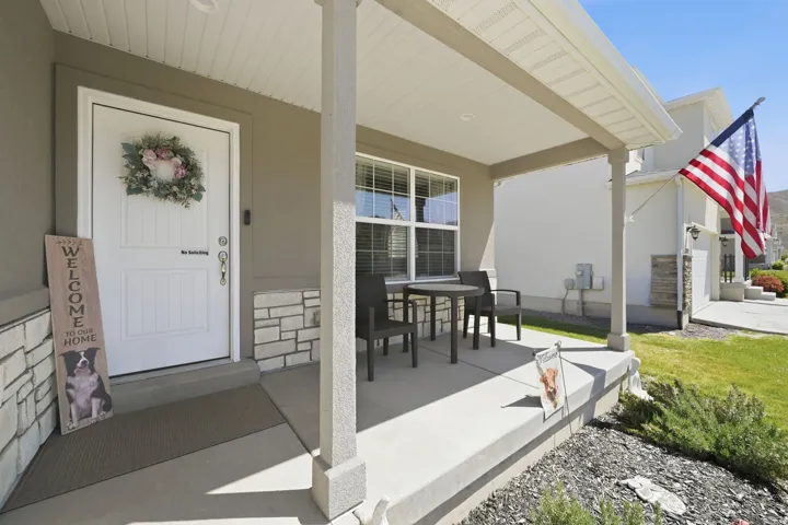 Covered front porch with concrete flooring and stone accent siding