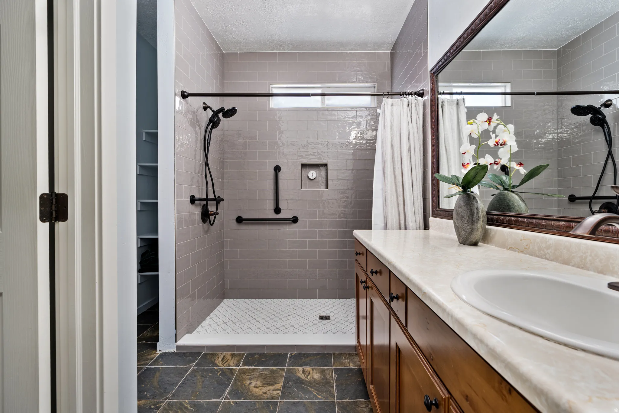 Bathroom featuring a single vanity with a solid surface countertop, an undermount sink, and a framed mirror