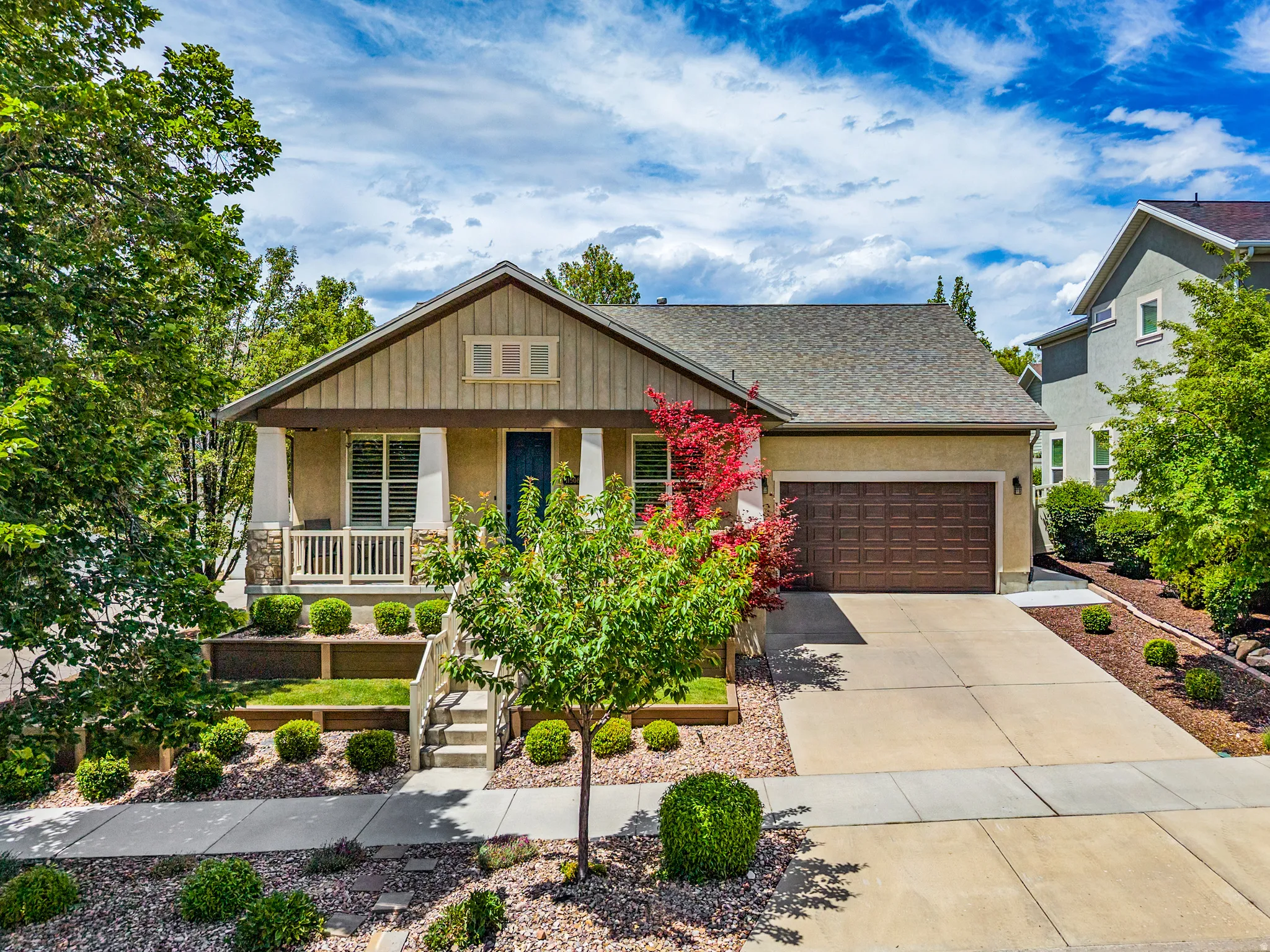 Craftsman-style home featuring a covered front porch with white columns and stone accents