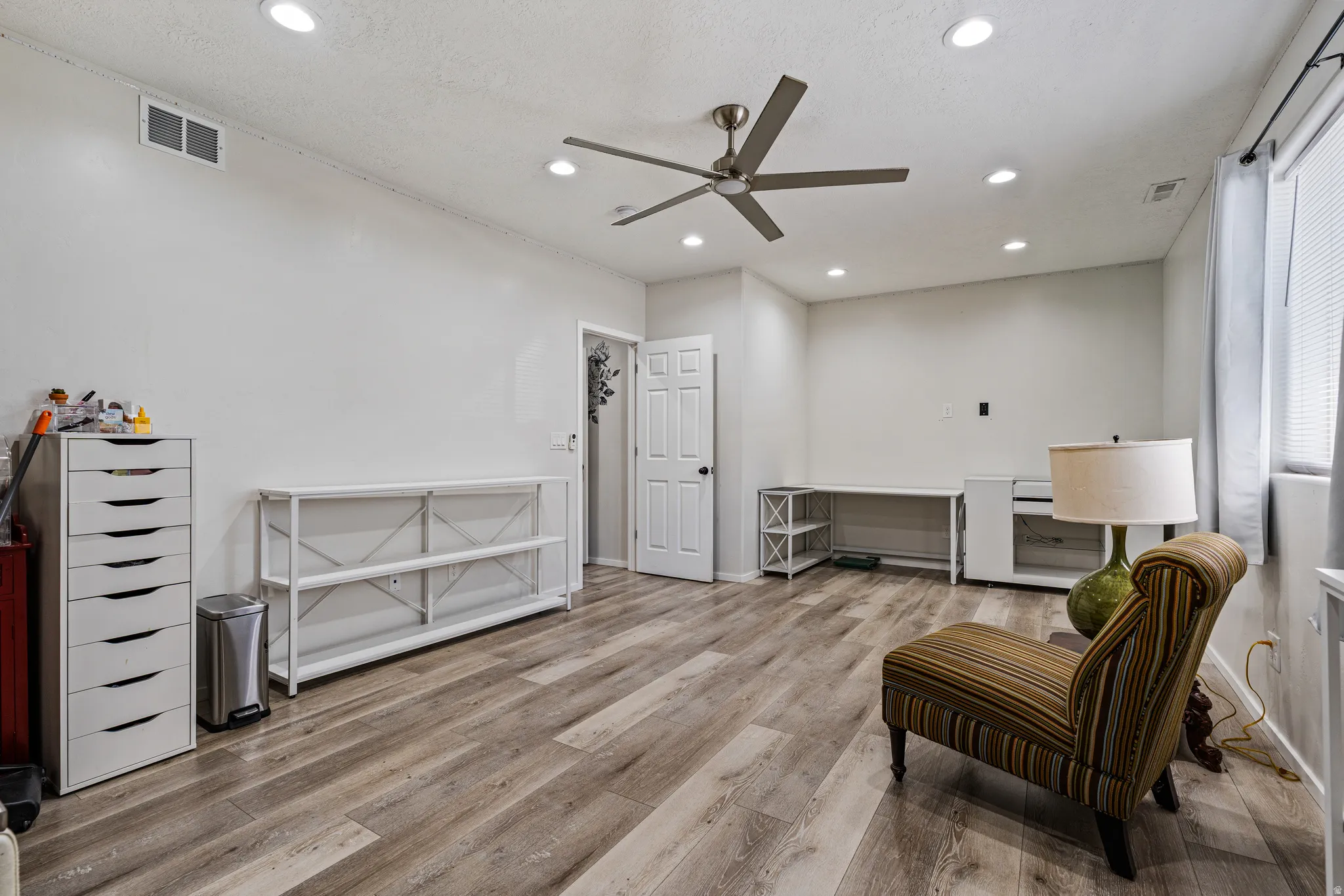 Spacious room featuring wood-finish flooring, recessed lighting, and a ceiling fan