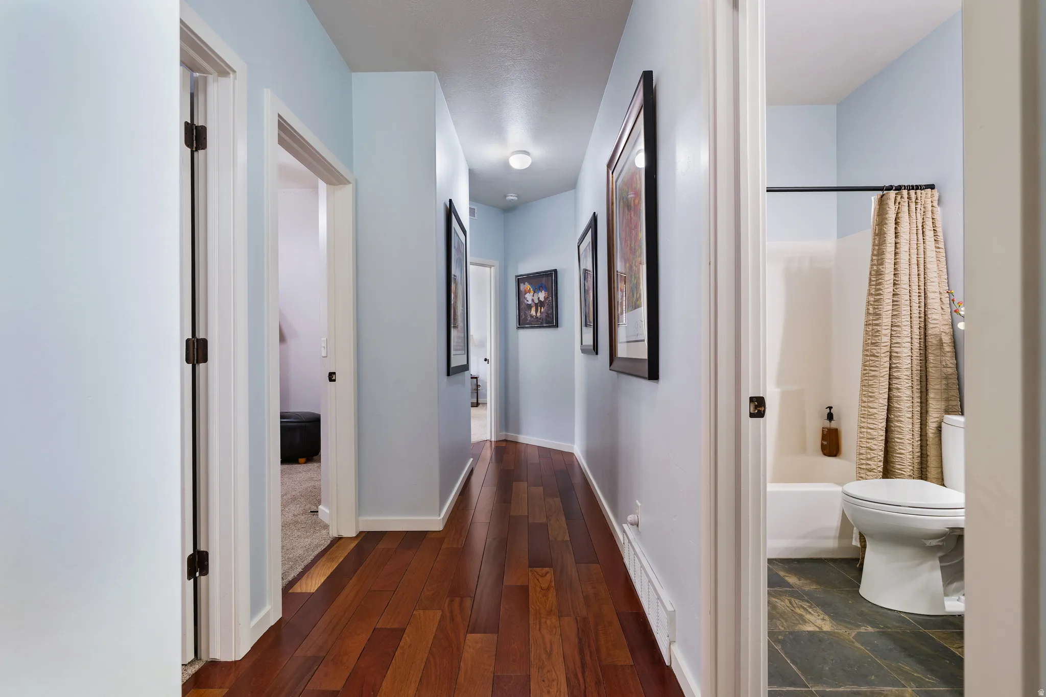 Hallway with wood-finish flooring, light blue wall paint, and white trim
