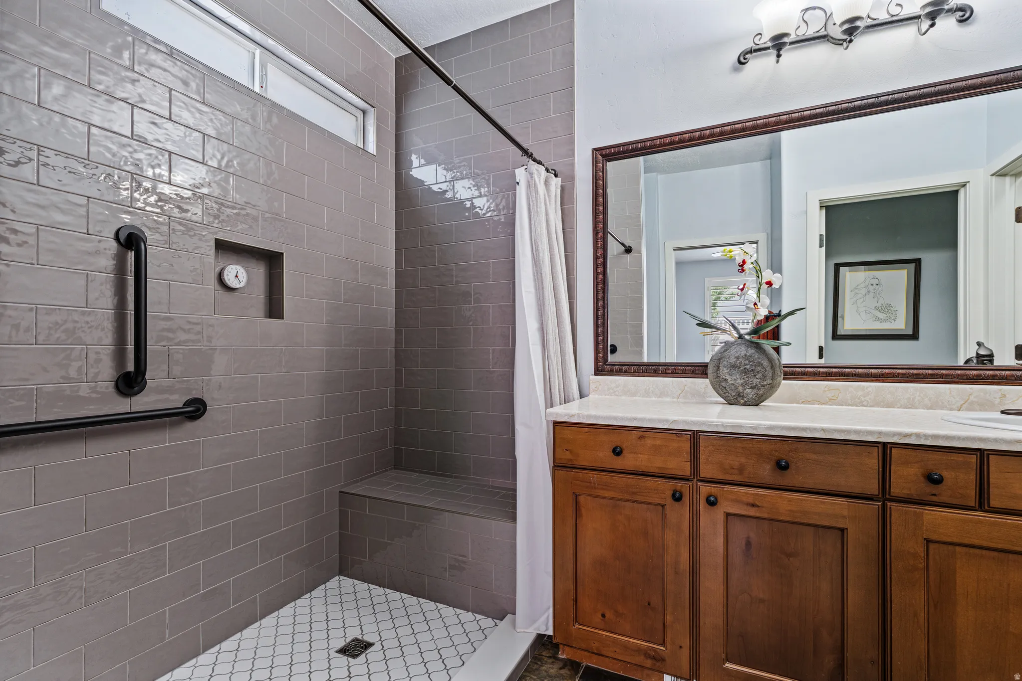 Bathroom featuring a walk-in shower with gray subway tile, a built-in shower bench, and a tiled shower niche