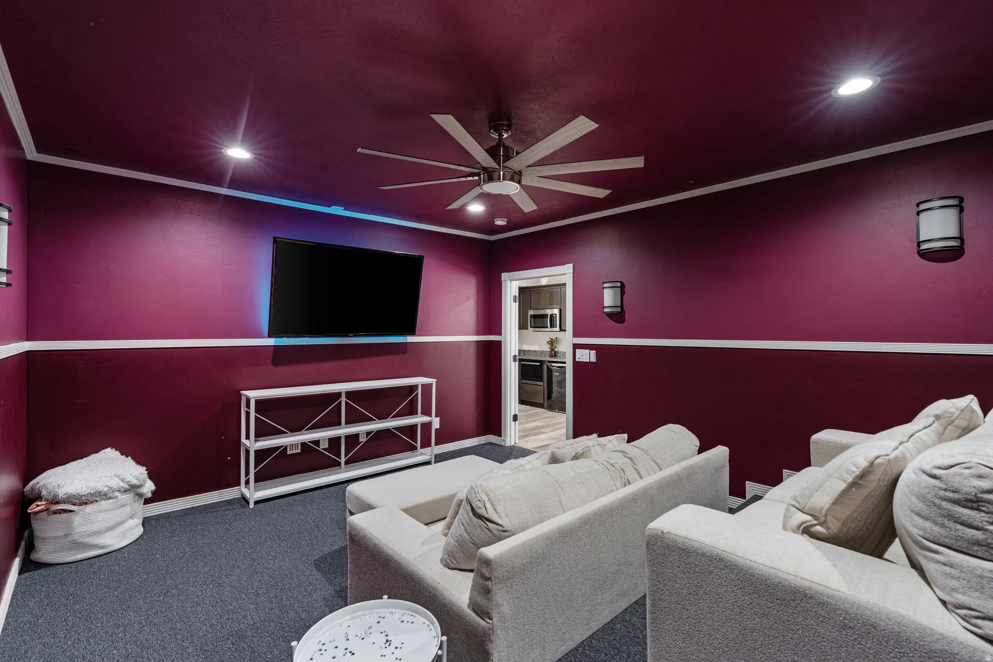 Dedicated media room featuring recessed lighting, a modern ceiling fan, wall-mounted sconces, and a mounted display