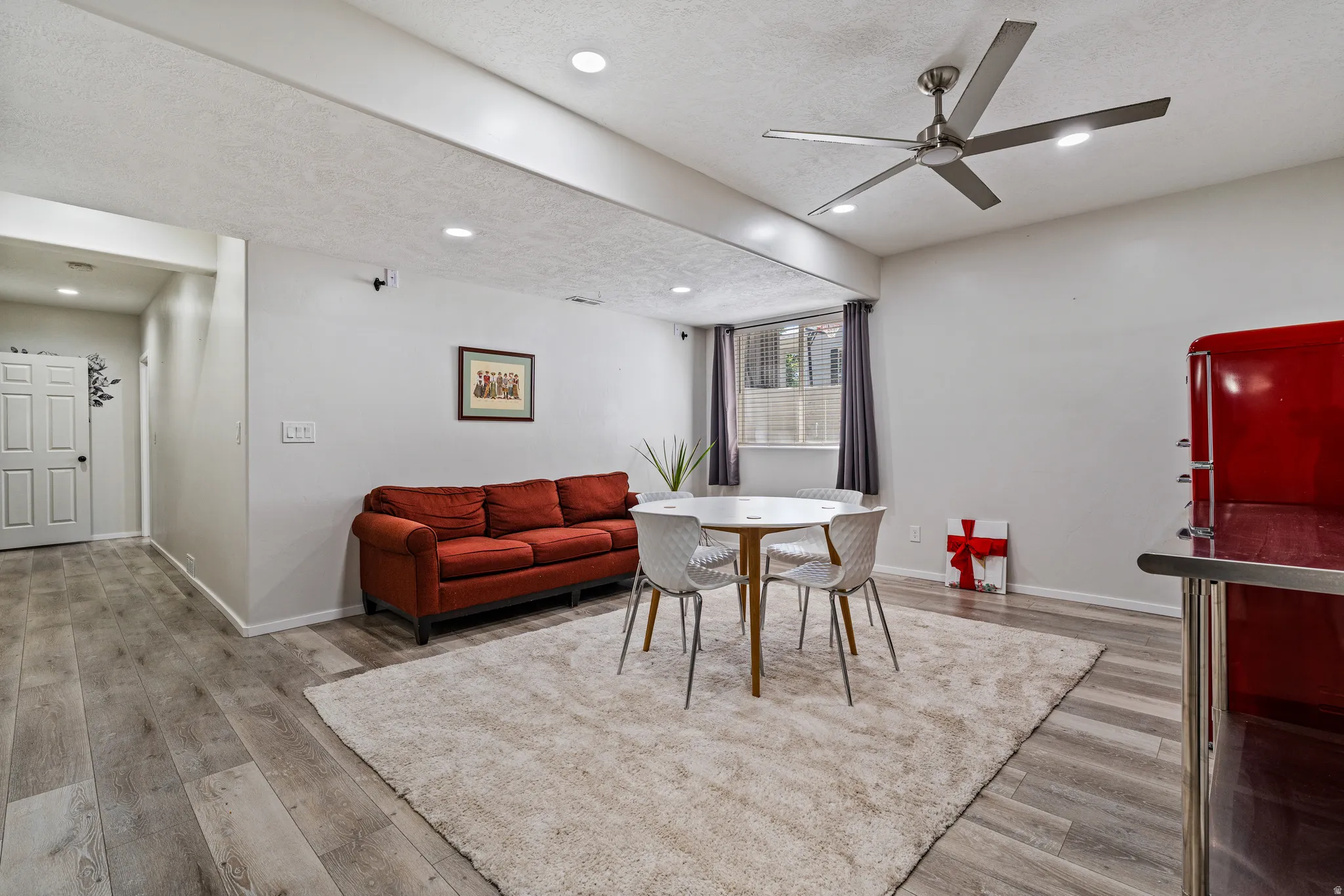 Spacious interior featuring wood-finish flooring, recessed lighting, a modern ceiling fan, and a window with blinds
