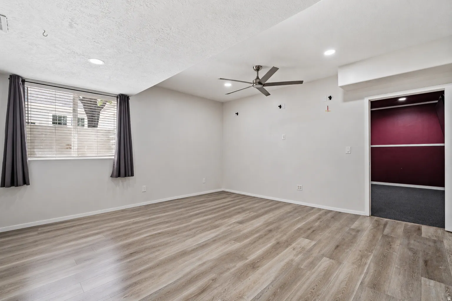 Spacious room featuring wood-finish flooring, recessed lighting, and a ceiling fan
