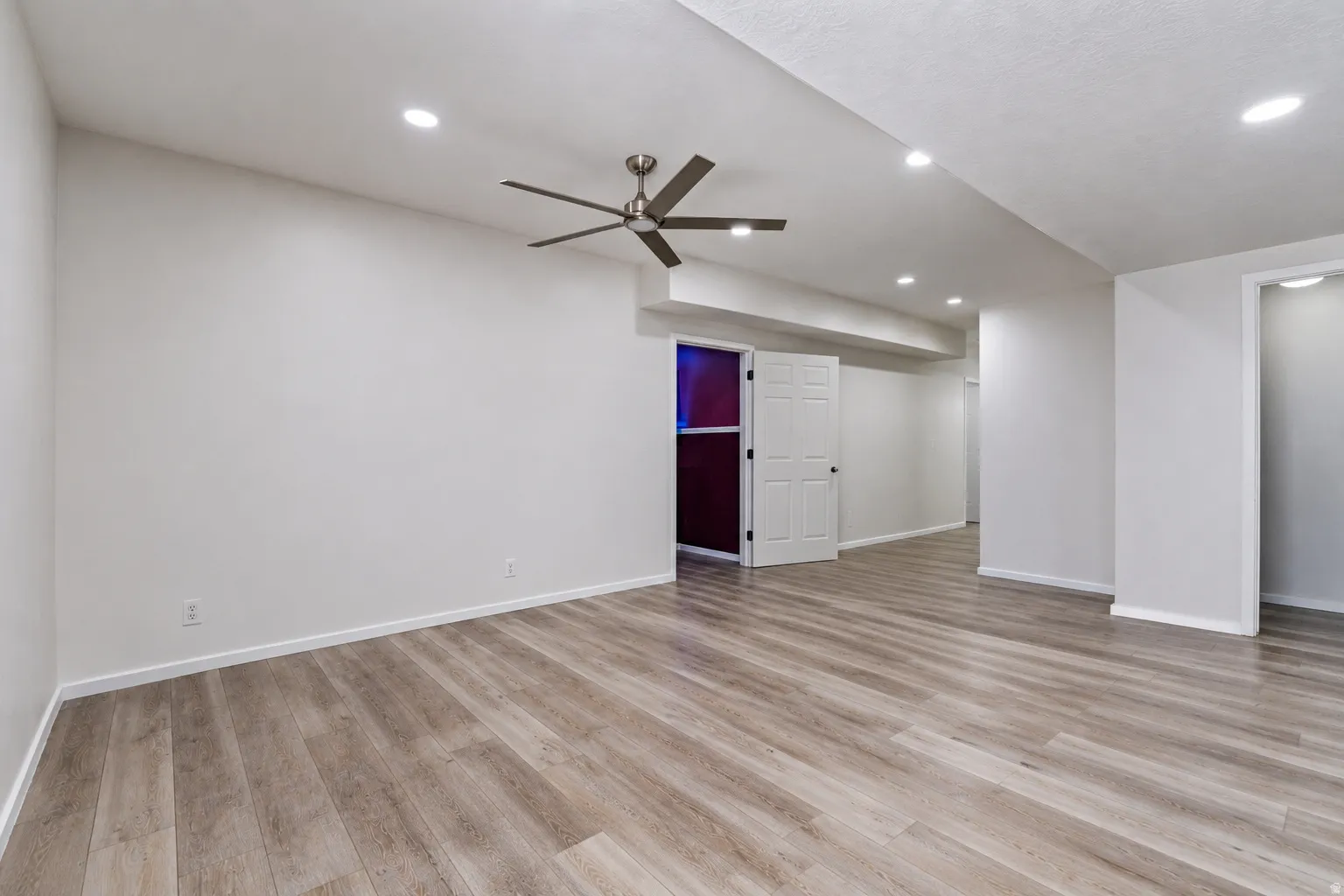 Spacious room featuring wood-finish flooring, recessed lighting, and a ceiling fan