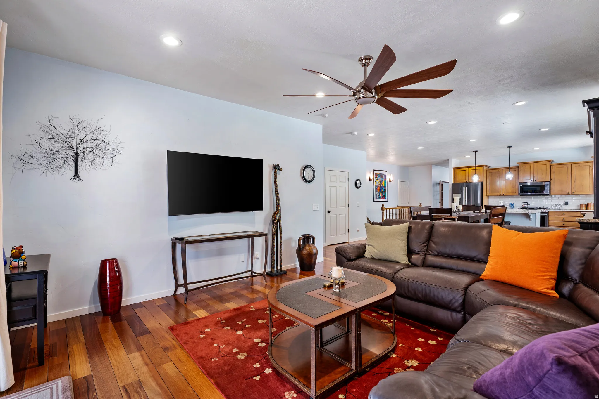 Open-concept living area with wood-finish flooring, recessed lighting, and a modern ceiling fan