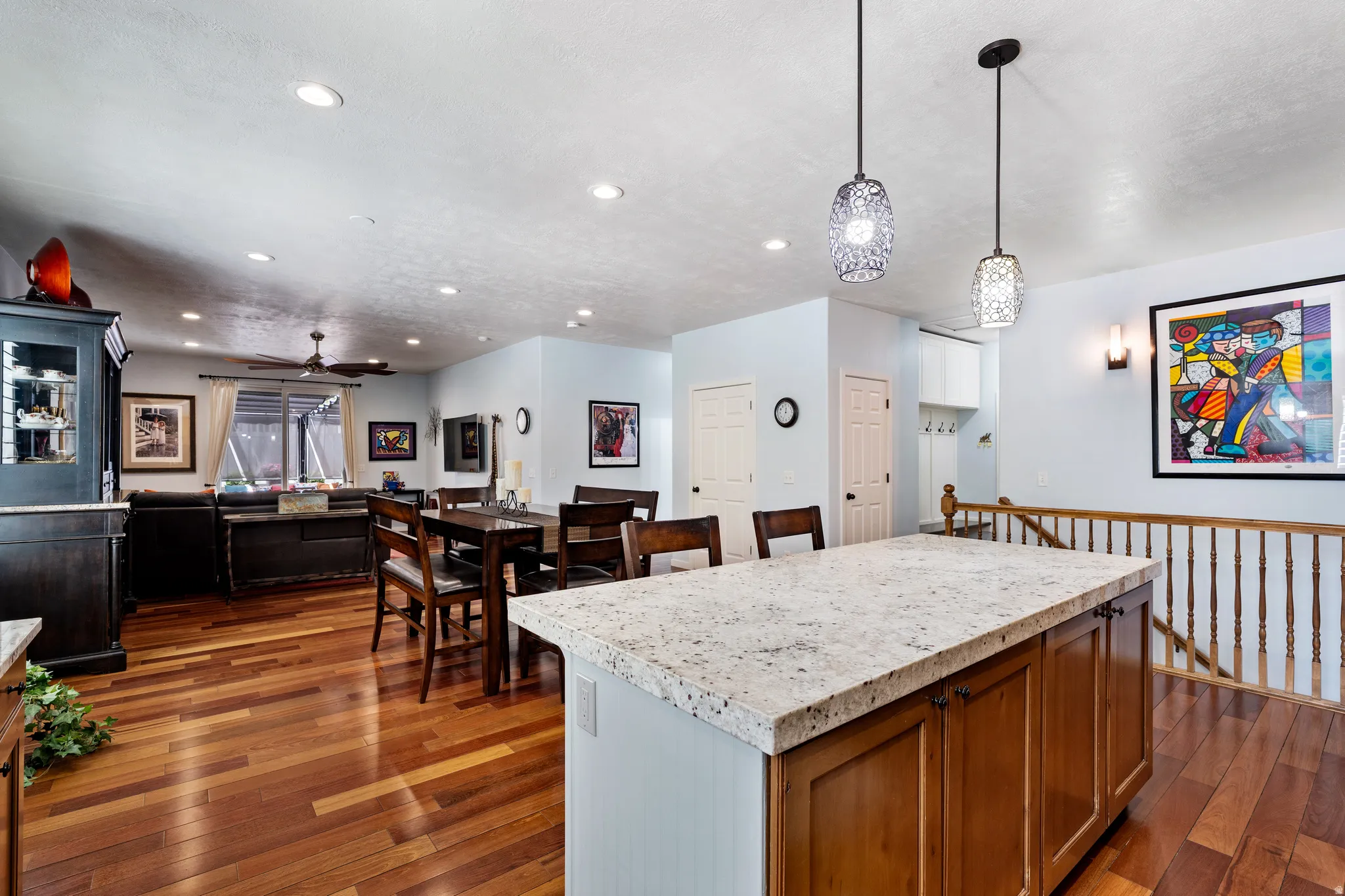 Kitchen island with a light-toned countertop, wood-finish cabinetry, and contemporary pendant lighting