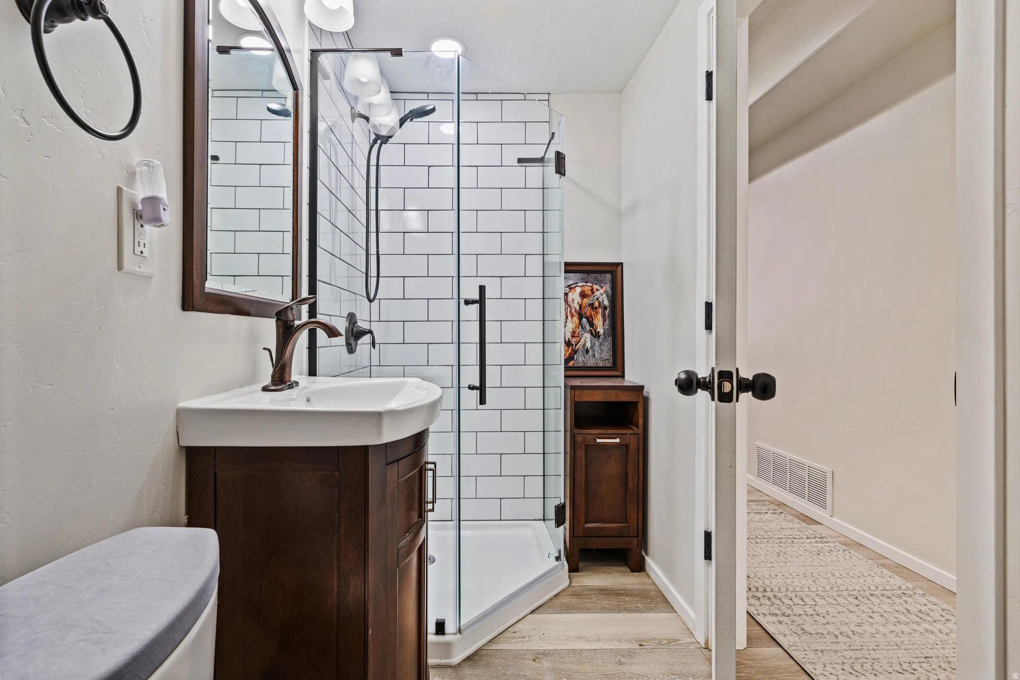 Bathroom featuring a dark wood-finish vanity with an integrated white sink, bronze-finish faucet, and coordinating framed mirror